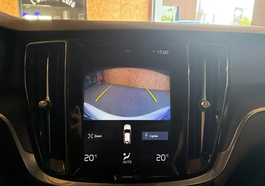 Vue rapprochée de l'écran central noir affichant la caméra de recul d'une Volvo V60 blanche, avec ventilation latérale visible.