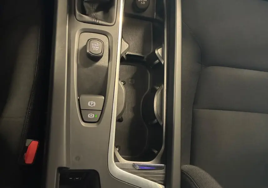 Vue plongeante sur la console centrale noire d’une Volvo V60 D3 2020, avec levier de vitesse manuel et boutons de démarrage.