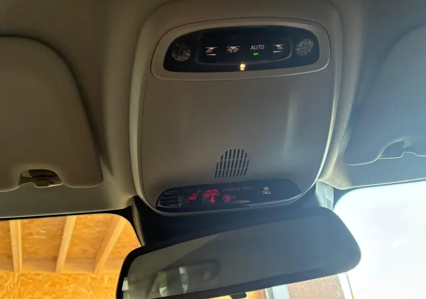 Vue intérieure en plongée du plafonnier gris avec commandes d’éclairage et rétroviseur intérieur d’une Volvo V60 blanche.