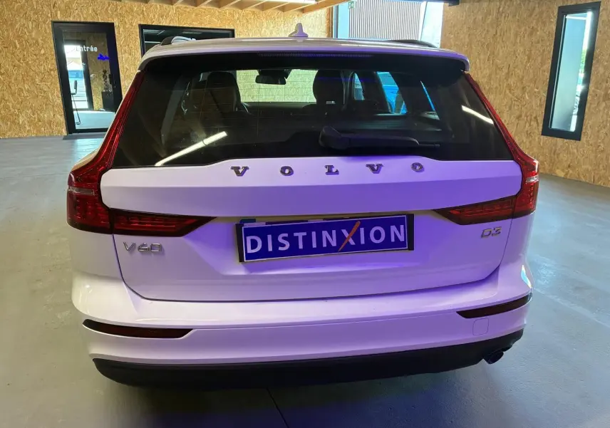Vue arrière d'un Volvo V60 D3 blanc 2020 avec feux arrière LED et plaque d'immatriculation Distinxion visible.