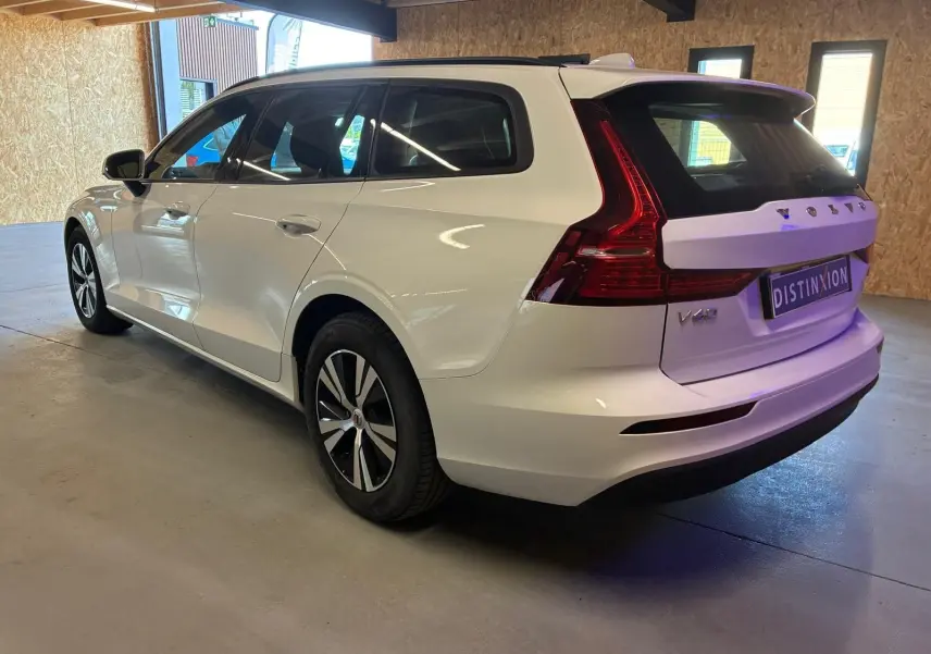 Volvo V60 D3 blanche vue 3/4 arrière droit dans un garage, avec feux arrière caractéristiques et jantes noires.
