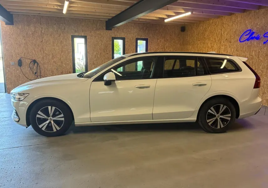 Vue de profil côté gauche d'un Volvo V60 D3 2.0 blanc, break 5 portes, stationné en intérieur.