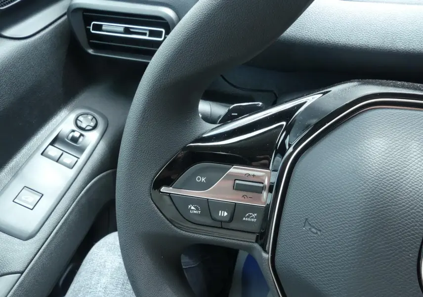 Gros plan sur les commandes gauche du volant noir du Peugeot Partner blanc, avec bouton OK et régulateur de vitesse.