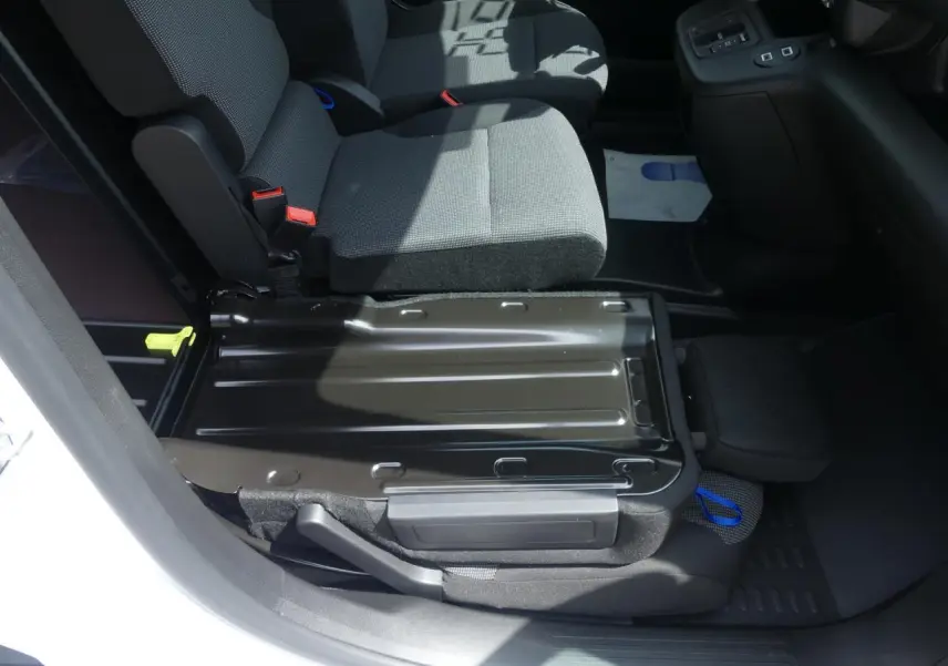 Vue intérieure côté passager du Peugeot Partner XL 2025, banquette rabattue avec tablette écritoire et sellerie tissu gris.