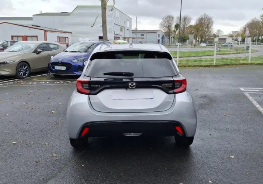 Vue arrière d'une Mazda2 hybride argent 2022 avec feux arrière reliés par une bande noire distinctive.