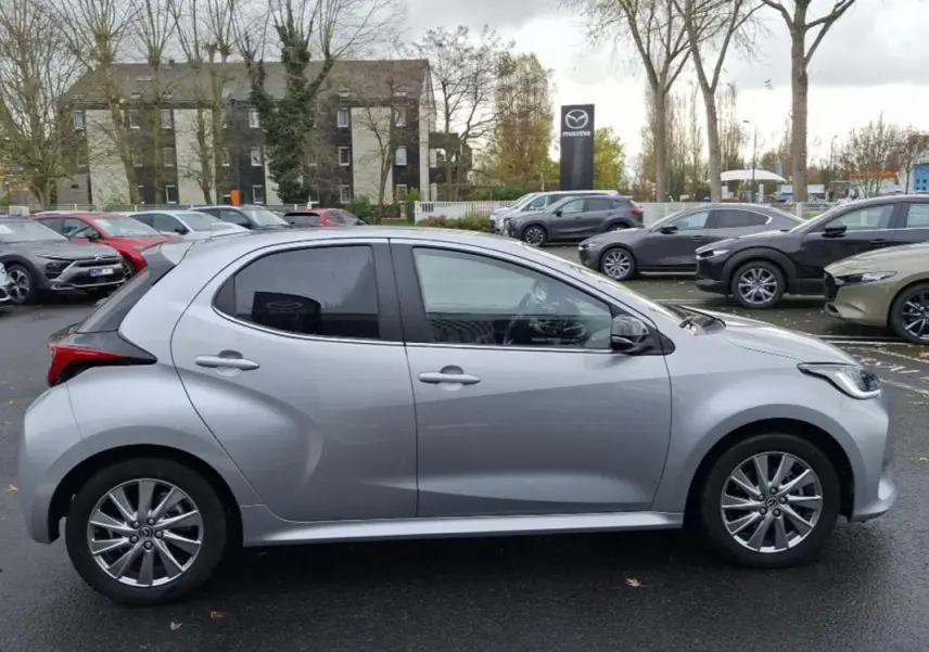 Profil côté gauche d'une Mazda2 hybride argent 2022, avec jantes alliage et lignes sculptées visibles.