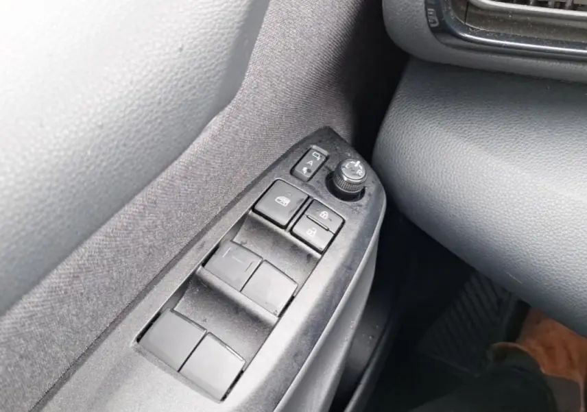 Gros plan sur les commandes des vitres et rétroviseurs côté gauche de la Mazda2 Hybrid 2022 avec intérieur gris.