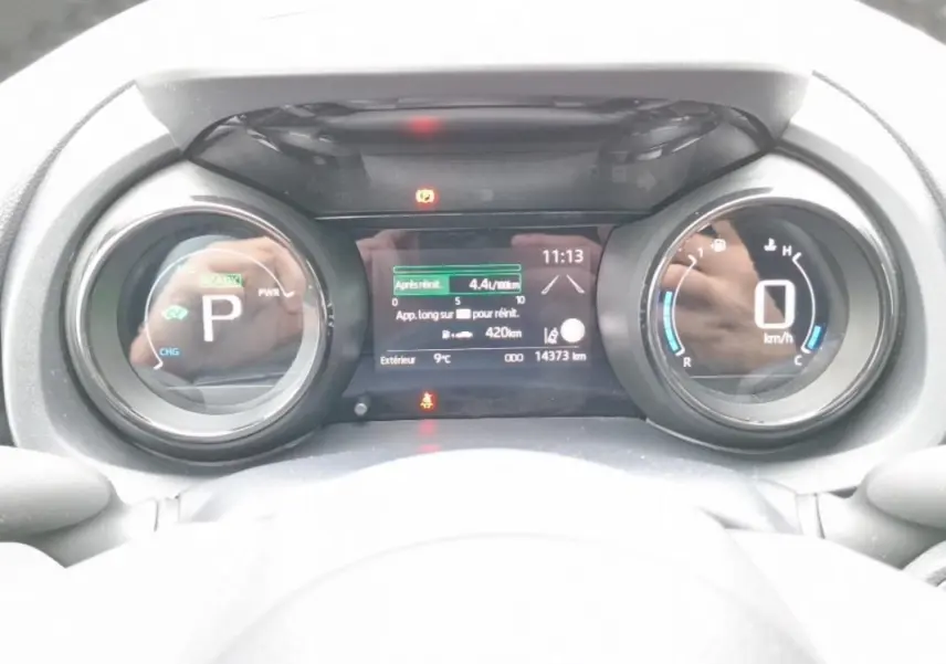 Tableau de bord numérique de la Mazda2 Hybrid 2022, affichant la vitesse à 0 km/h et la consommation instantanée.