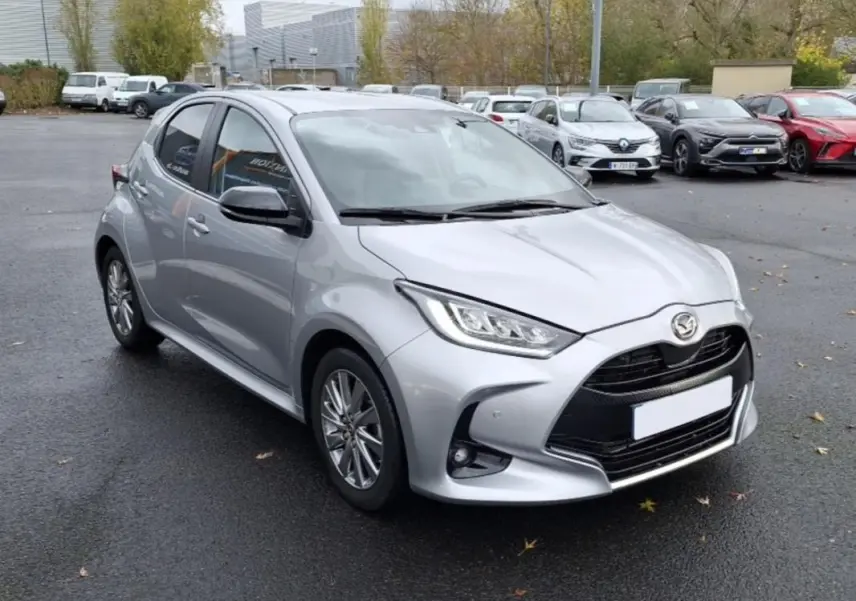 Vue 3/4 avant d'une Mazda2 hybride argent 2022 avec calandre noire et phares LED distinctifs.