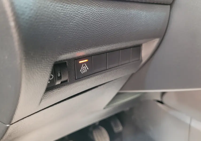 Gros plan sur le tableau de bord côté gauche du Peugeot 208 gris foncé, avec bouton d'alerte de franchissement de ligne activé.
