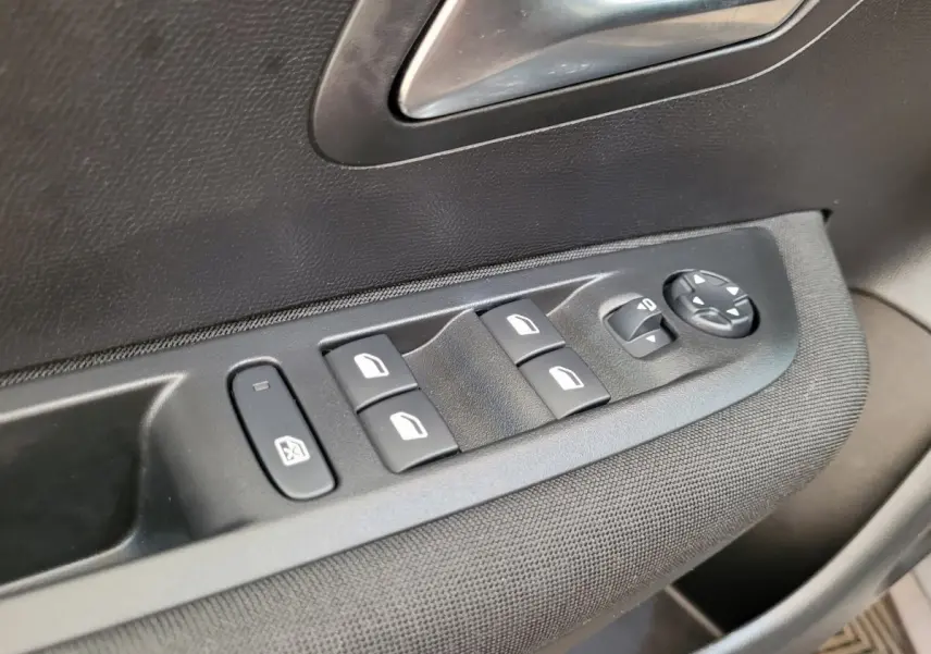 Gros plan sur les commandes des vitres électriques côté conducteur de la Peugeot 208 gris foncé 2023 Active Pack.
