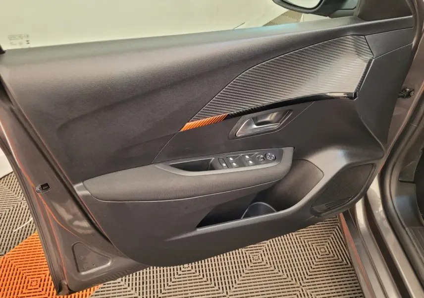 Vue côté intérieur de la porte avant gauche de la Peugeot 208 gris foncé avec insert décoratif noir et orange.