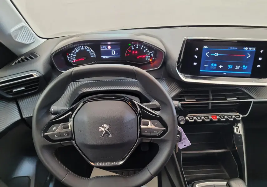 Vue intérieure centrée sur le volant cuir et tableau de bord numérique de la Peugeot 208 2023 gris foncé.