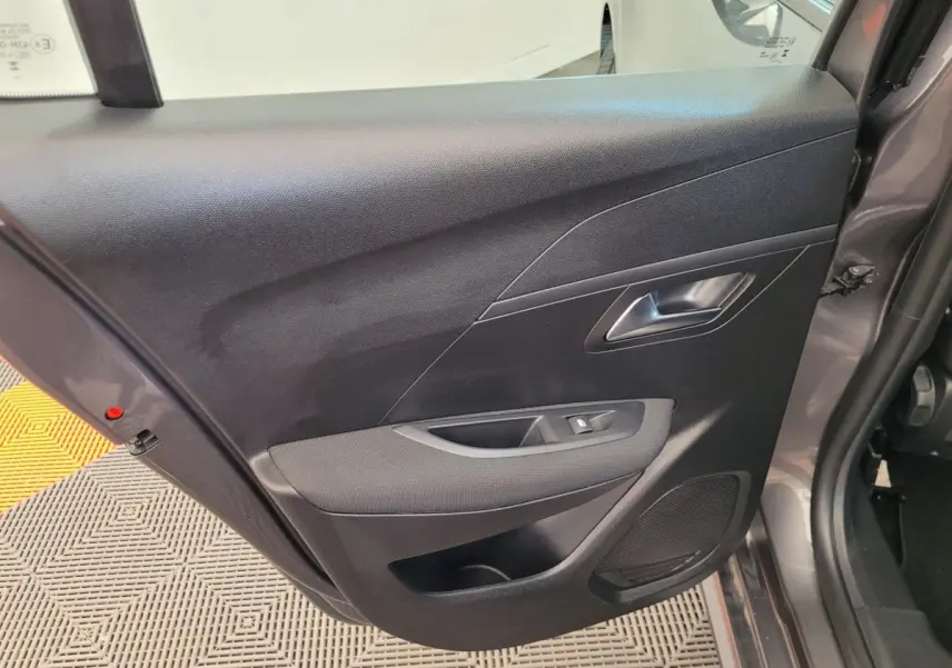 Vue rapprochée de la porte arrière droite gris foncé de la Peugeot 208 2023 avec commande de vitre et haut-parleur intégré.