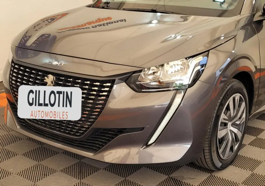 Vue 3/4 avant droit d'une Peugeot 208 gris foncé avec calandre distinctive et feux LED en forme de griffes.