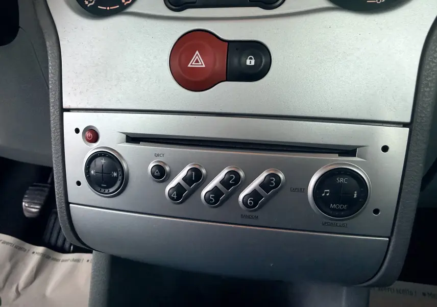 Vue rapprochée de la console centrale argentée du Renault Modus 2011, avec boutons de commande audio et alerte.