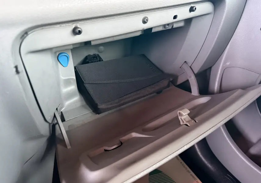 Vue intérieure du vide-poche côté passager d'une Renault Modus beige, avec un étui noir marqué Renault.