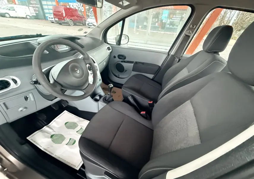 Vue intérieure côté conducteur de la Renault Modus 2011, sièges tissu gris et noir avec volant cuir noir.