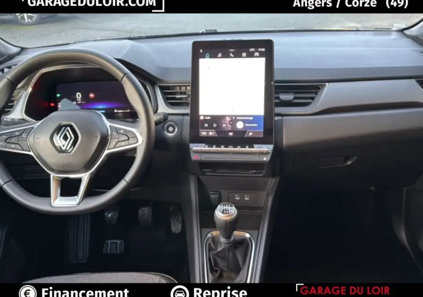 Vue intérieure du tableau de bord du Renault Captur 2025 gris foncé, avec volant multifonction et écran tactile vertical central.