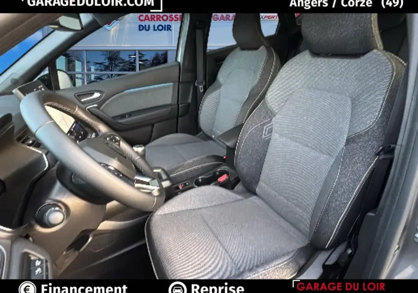 Vue intérieure côté conducteur du Renault Captur 2025 gris foncé, montrant les sièges en tissu et le volant multifonction.