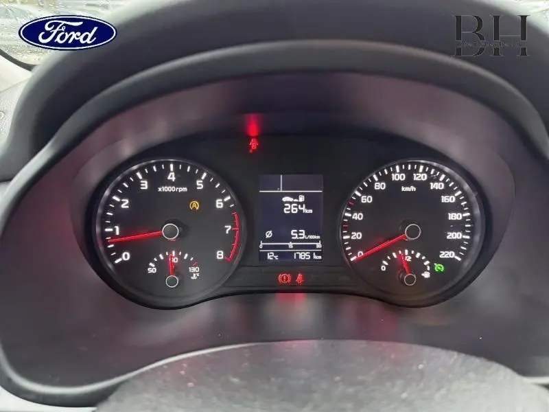 Vue rapprochée du tableau de bord noir d'une KIA RIO 2018 avec compte-tours, compteur de vitesse et écran digital central.