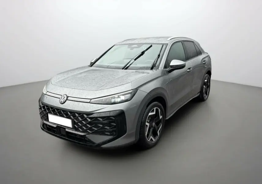 Volkswagen T-Roc gris loup en 3/4 avant droit, avec jantes alu noires et toit surélevé sous pluie légère.