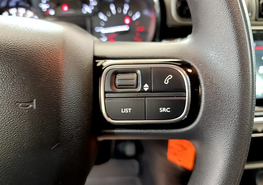 Gros plan sur les commandes gauche du volant noir de la Citroën C3 2021, avec boutons de gestion audio et appels.