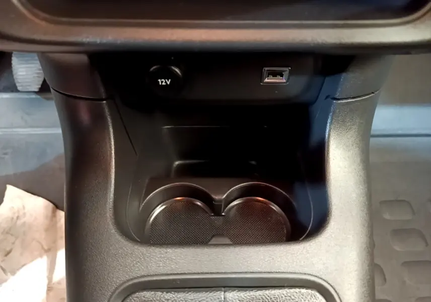 Gros plan sur la console centrale noire avec prise 12V et port USB du Citroën C3 blanc, version 2021.