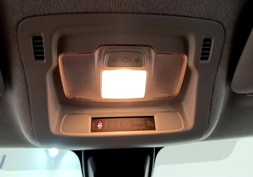 Plafonnier intérieur allumé avec témoin de ceinture de sécurité rouge dans une Citroën C3 blanche, vue du plafond avant.