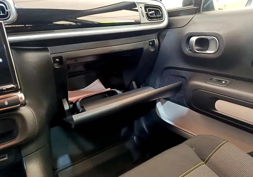 Intérieur de la Citroën C3 blanc, vue côté passager montrant la boîte à gants ouverte et la porte avec haut-parleur intégré.