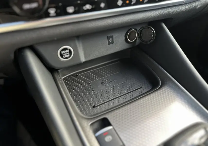 Gros plan sur la console centrale noire du Nissan Qashqai 2025, avec bouton start/stop et chargeur sans fil.