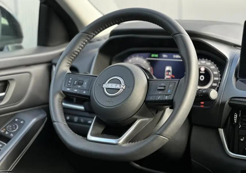 Vue rapprochée du volant cuir noir du Nissan Qashqai 2025 avec commandes intégrées et tableau de bord numérique.