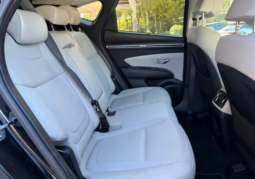 Vue intérieure arrière gauche du Hyundai Tucson 2022 noir, montrant la banquette claire en cuir et les détails de la porte.