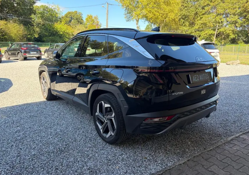Vue 3/4 arrière droite du Hyundai Tucson noir 2022 avec barres de toit et feux arrière LED distinctifs.