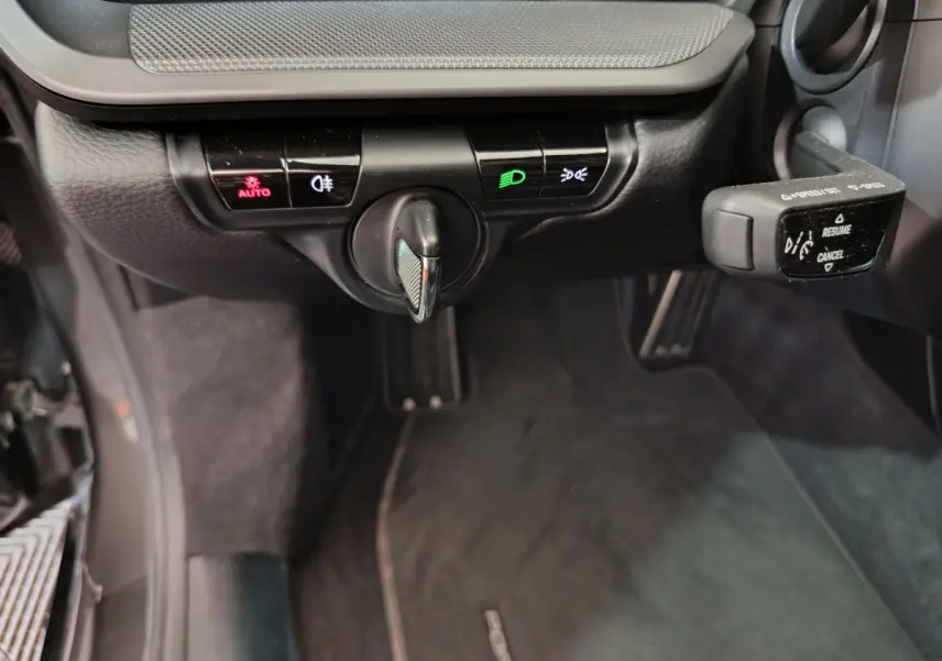 Gros plan sur les commandes d'éclairage et régulateur de vitesse du tableau de bord noir d'une Porsche 911 Carrera 4S 2019.