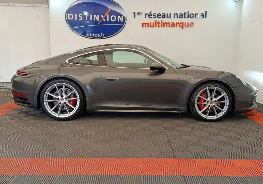 Profil côté gauche d'une Porsche 911 Carrera 4S Coupé gris foncé avec jantes alliage et étriers de frein rouges.