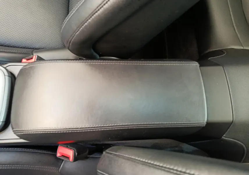 Vue rapprochée de l'accoudoir central en cuir noir et des ceintures de sécurité rouges dans l'habitacle d'une Porsche 911 Carrera 4S Coupé 2019.