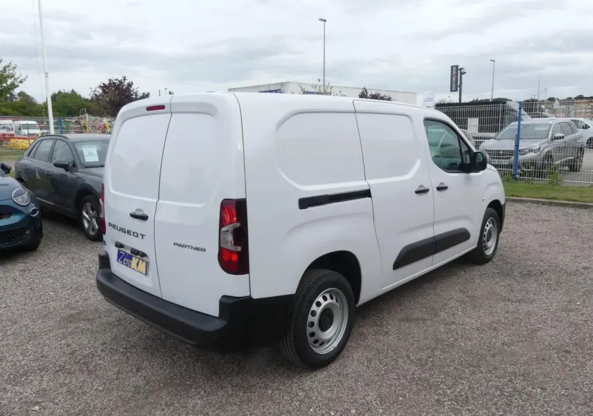 Vue 3/4 arrière droit d'un utilitaire Peugeot Partner blanc avec portes arrière battantes et protections latérales noires.