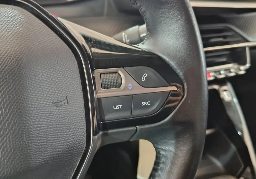 Gros plan sur les commandes du volant cuir noir de la Peugeot 208 PureTech 100 S&S Active Business 2020.