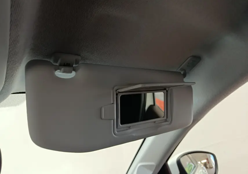 Miroir de courtoisie ouvert sur le pare-soleil côté conducteur d'une Peugeot 208 blanche, vue intérieure.