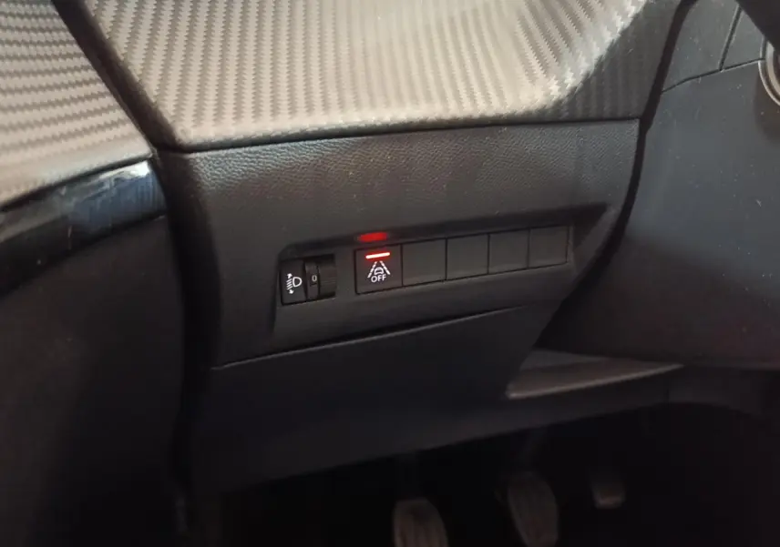 Détail du tableau de bord côté conducteur du Peugeot 208 blanc 2020 avec bouton d'assistance désactivée éclairé en rouge.