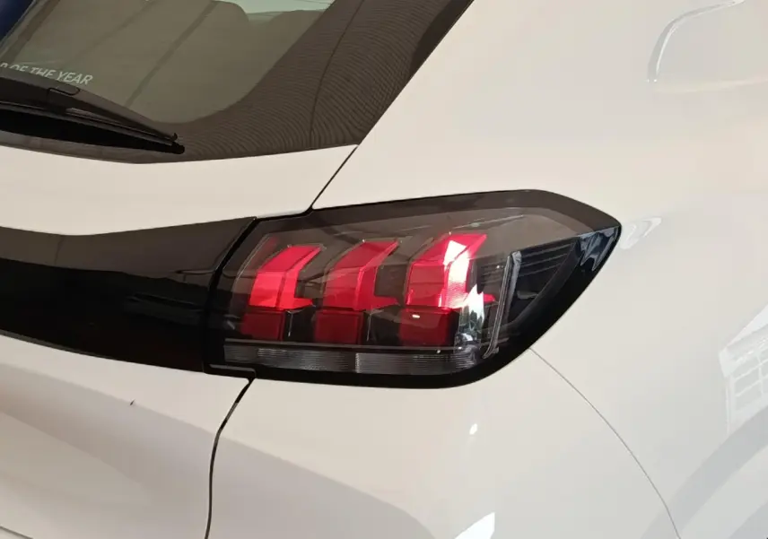 Gros plan sur le feu arrière droit rouge et noir d'une Peugeot 208 blanche vue de l'arrière.