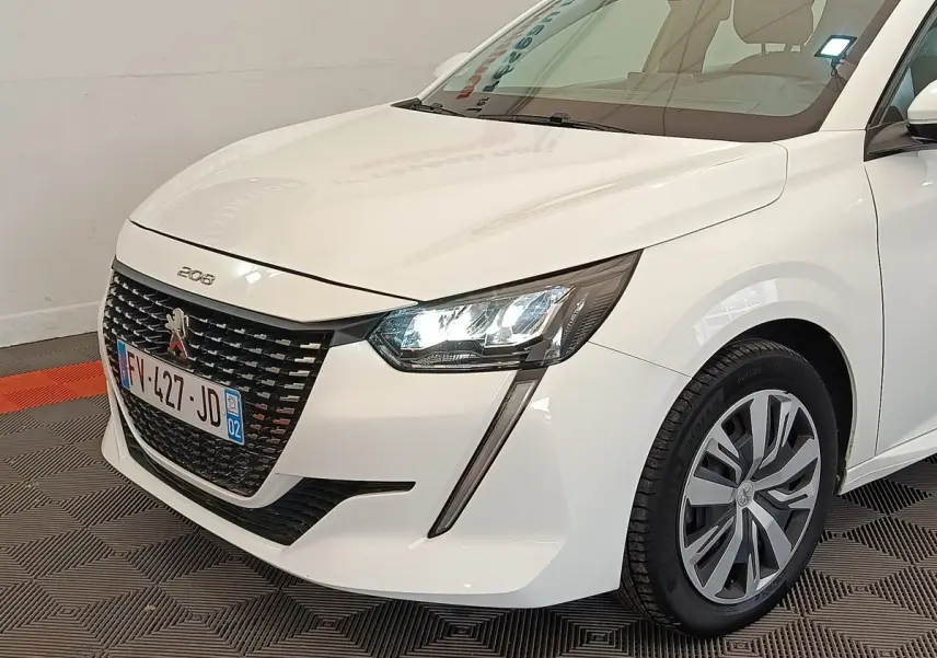 Vue 3/4 avant droit d'une Peugeot 208 blanche avec phares LED et calandre noire distinctive.
