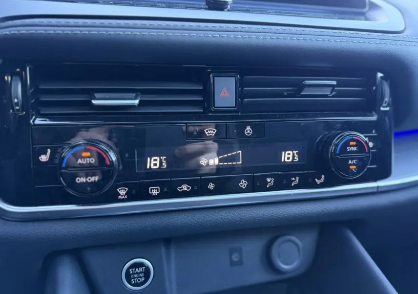 Gros plan sur la console centrale du Nissan Qashqai 2025, affichage digital de la climatisation bi-zone et bouton start/stop.