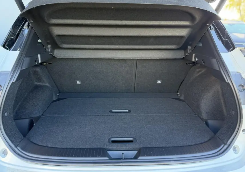 Coffre ouvert du Nissan Qashqai blanc nacré, vue arrière montrant un plancher de coffre plat et modulable.