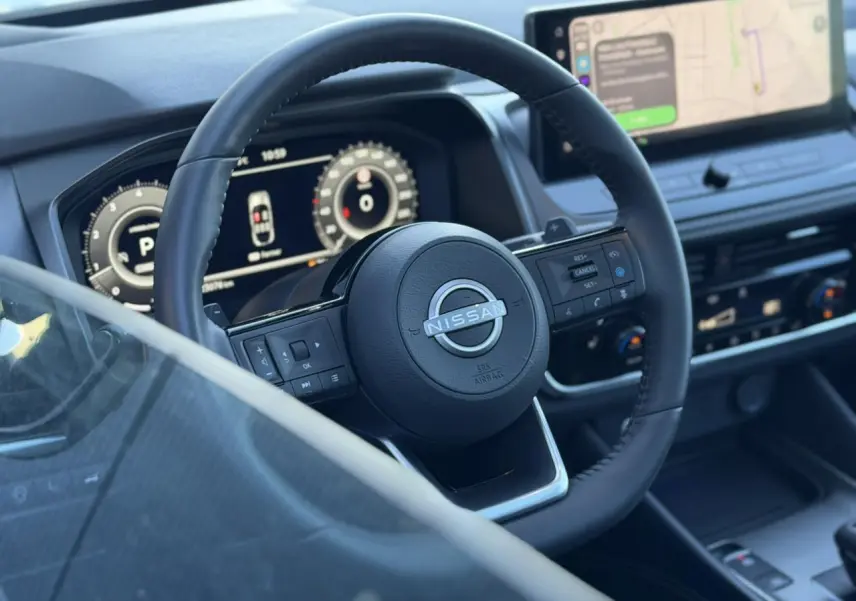 Vue rapprochée du volant cuir noir et du combiné numérique du Nissan Qashqai 2025 avec écran tactile et affichage tête haute.