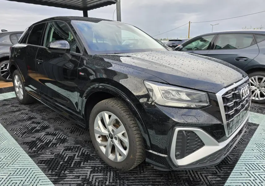 Audi Q2 noir mythic vue 3/4 avant droit, avec calandre S-Line et jantes aluminium 5 branches doubles.