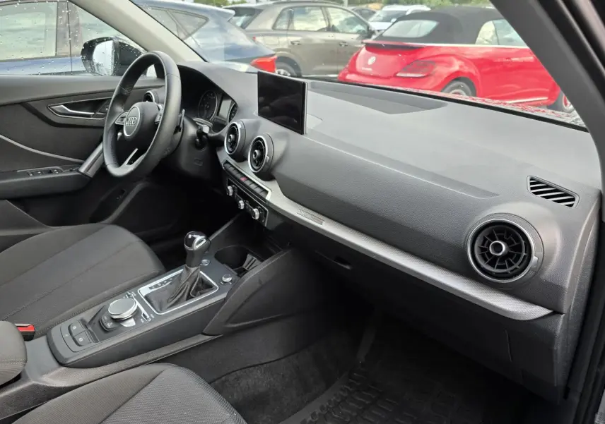 Intérieur de l'Audi Q2 35 TFSI 2023 en noir mythic, vue côté conducteur sur tableau de bord et console centrale.
