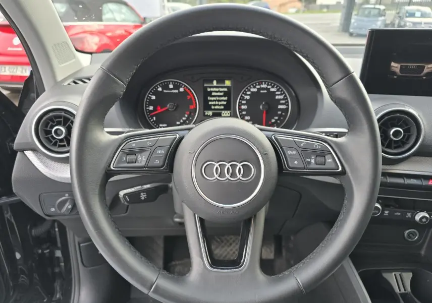 Volant cuir multifonction Audi Q2 35 TFSI 2023 vu de face avec tableau de bord et compteurs analogiques.