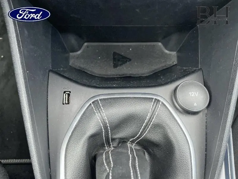 Gros plan sur la console centrale de la Ford Fiesta blanche, montrant le levier de vitesse manuel et prise 12V.